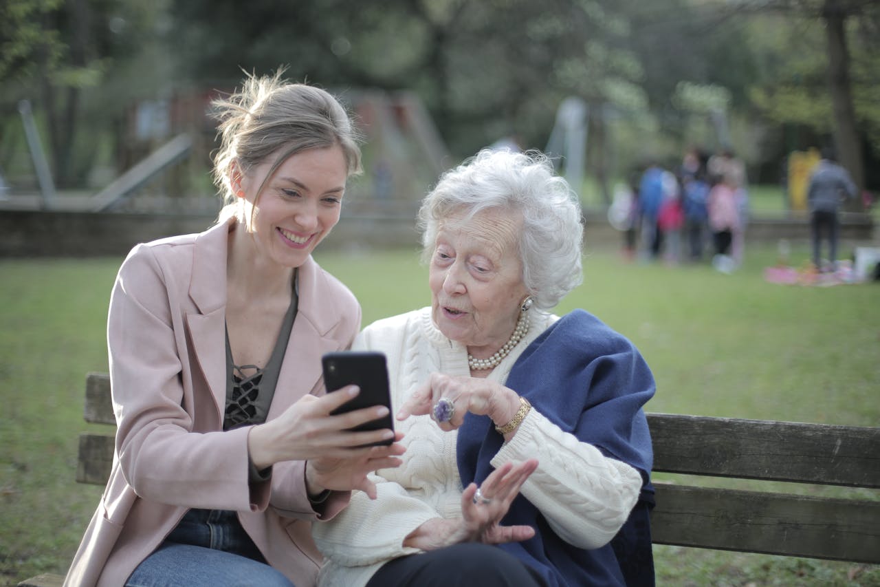 The Art of Drawing Readers In: Your attractive post title goes here Delighted female relatives sitting together on wooden bench in park and browsing mobile phone while learning using